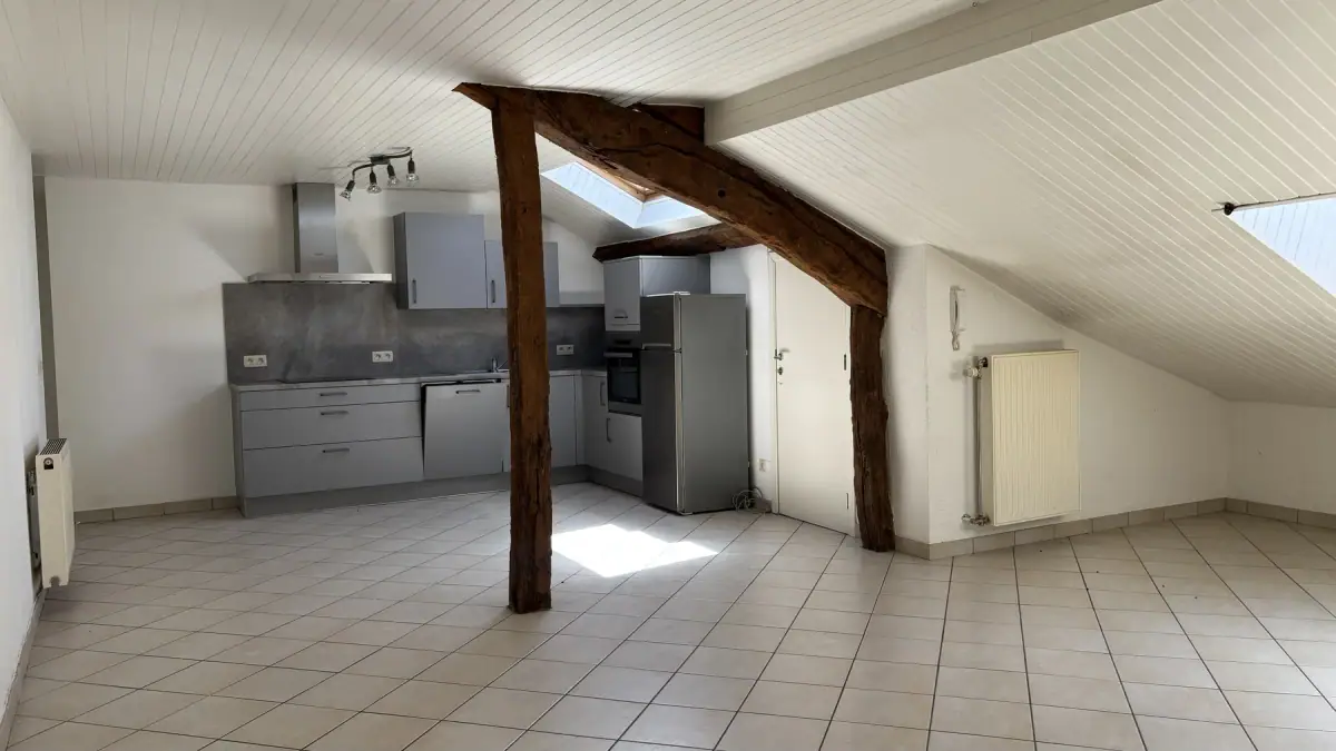 La pièce de vie sous poutres de l’appartement